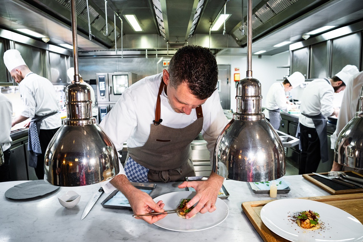 Chef preparando un plato en cocina abierta